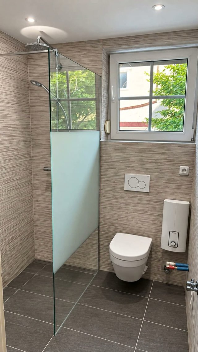 Dasselbe Bad nach der Sanierung: Walk-in-Dusche mit Glaswand am Fenster, Riemchenfliesen, wandhängendes WC